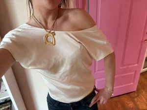 Vit offshoulder topp - Snygg offshoulder topp i vit satin med korta ärmar. Lite trådar på framsidan. 