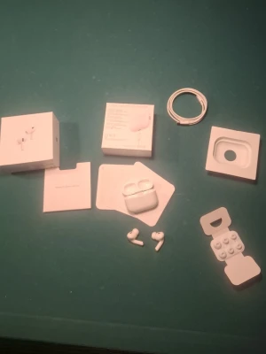 Apple AirPods Pro gen 2med laddningsetui - Säljer ett par vita Apple AirPods Pro med trådlöst laddningsetui. Hörlurarna har in-ear-design, silikonproppar i olika storlekar och levereras med originalkartong, laddkabel och extra öronproppar. Snygg och stilren design i blank plast, perfekt för dig som gillar Apple.
