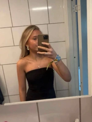 Svart axelbandslös body - Säljer en svart axelbandslös tubtopp med tight passform och stretchig! använt en gång🥰