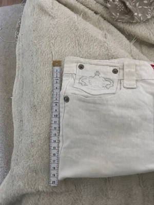 Vita korta shorts med låg midja - Säljer ett par vita, korta shorts med låg midja och knappgylf. De har en enkel design utan synliga loggor eller mönster och är gjorda i ett stretchigt bomullsmaterial. Perfekta för sommardagar och passar till det mesta i garderoben.