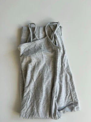 Grå långklänning från Gina Tricot - Snygg grå linnetopp från Gina Tricot med smala axelband. Klänningen är i softtouch och har storlek S. 