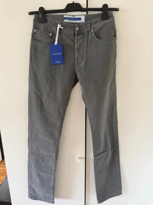 Grå jeans från Jacob Cohën - Snygga grå jeans från Jacob Cohën med klassisk femficksmodell och raka ben. Jeansen har diskret broderad logga på myntfickan och silverfärgade nitar. Tillverkade i mjuk denim för en bekväm känsla. Perfekta för en stilren och avslappnad look.