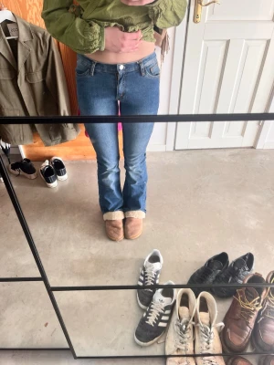 Blå bootcut jeans med låg midja - Säljer ett par klassiska blå bootcut jeans med låg midja och fem fickor. Jeansen har en lätt tvättad look och sitter tajt över låren för att sedan bli vidare nedtill.  Jag tycker att jeansen är väldigt tajta så skulle rekommendera för er som är strl 158. Kontakta för fler frågor som midjemått osv. När jag köpte jeansen hade de inget hål för knappen att sticka igenom så det har jag gjort själv. Därför är hålet lite känsligt…. Men funkar fortfarande!
