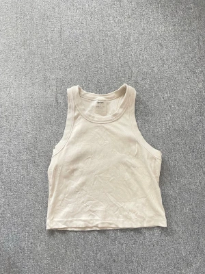 Beige cropped tanktop från Aim’n - Snyggt beige cropped tanktop från Aim’n i mjuk bomull. Modellen har breda axelband och rundad halsringning