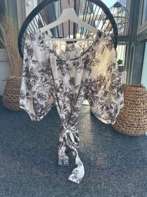 Blommönstrad blus med 3/4 lång ballongärm  - Knyt i midjan. Strykfri.