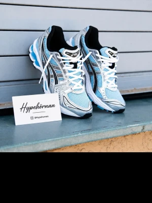 ASICS sneakers i blått och silver - Snygga ASICS sneakers med mesh i ljusblått, detaljer i silver och svart samt vita och blå inslag på sulan. Skorna har klassisk snörning, sportig vibe och ikoniska ASICS-ränder på sidorna. Perfekta för dig som gillar streetstyle och sportig look.