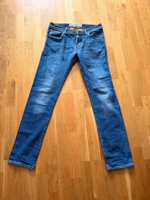 Blå raka jeans från jacob cohën - Säljer ett par klassiska blå jeans från jacob cohën med rak passform och diskreta slitningar på framsidan. Jeansen har fem fickor, normal midja och är tillverkade i denim. Perfekta för en avslappnad och stilren look. Limited edition modell:688💫