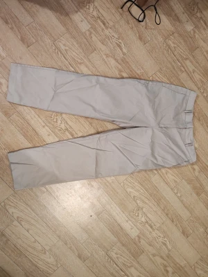 Beiga chinos byxor dam stl 38  - Snygga beiga chinos med rak passform och klassiska bälteshällor. Byxorna har en stilren look och är tillverkade i ett mjukt bomullstyg som känns bekvämt hela dagen. Perfekta för dig som gillar en clean och enkel stil. Mycket bra skick. 