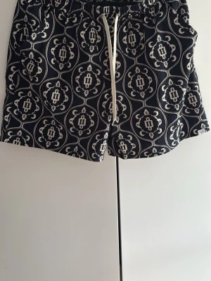 Les deux badbyxor  - Snygga badbyxor i marinblått med vitt mönster och vita snören i midjan. Klassisk  modell med elastisk midja och tillverkade i snabbtorkande material. Pris kan diskuteras vid snabb affär. 