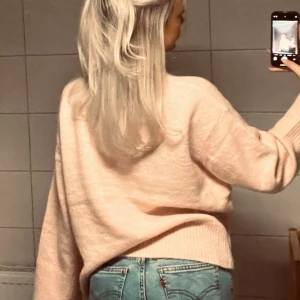 Ljusrosa stickad tröja - Mysig ljusrosa stickad tröja med avslappnad passform och långa ärmar. Tröjan har ribbade muddar och är perfekt att matcha med jeans för en chill look.