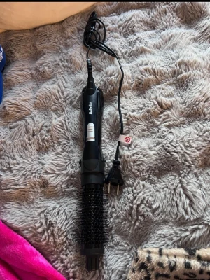 BaByliss svart varmluftsborste - Elektrisk varmluftsborste från BaByliss i svart plast med silverfärgade knappar. Borsten har rund form och är perfekt för styling och volym. Utrustad med sladd och EU-kontakt. Smidig att använda för att fixa håret.