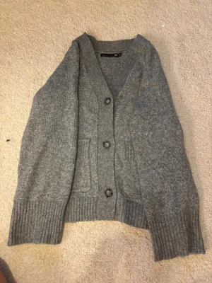 Grå kofta från 157 med knappar - Mysig grå kofta från 157 med tre stora knappar framtill och två fickor. Supersöt att bara slänga över sig och få en bra outfit! 