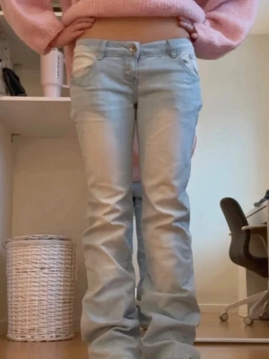 Ljusblå bootcut jeans - Säljer ett par ljusblå bootcut jeans med låg midja och klassisk femficksdesign. Jeansen har en snygg tvättad look och är tillverkade i ett mjukt denimtyg som sitter skönt. Perfekta för dig som gillar en avslappnad och trendig stil.