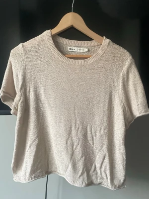 Beige stickad topp från ONLY - En enkel och snygg beige stickad topp från ONLY med rund halsringning och korta ärmar. Toppen har en loose passform och är tillverkad i ett mjukt stickat material. Superfin och perfekt för sommaren. Storlek L men passar mindre❣️