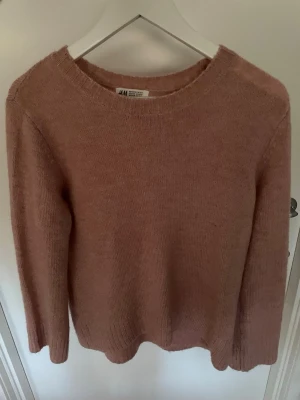 Rosa stickad tröja från H&M - En enkel och snygg stickad tröja i ljusrosa från H&M. Tröjan har rund halsringning, långa ärmar och är gjord i ett mjukt material som känns skönt mot huden. 