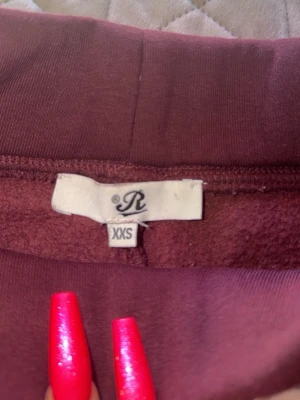 Russemerch Vinröda mjukisbyxor  - Vinröda mjukisbyxor från Russerch med vita snören i midjan och praktiska fickor. Byxorna har en rak passform och är tillverkade i ett mjukt material som är perfekt för chill dagar. Snygg färg som är enkel att matcha med hoodies eller t-shirts. Jag är 158 å de va på gränsen till för korta.!