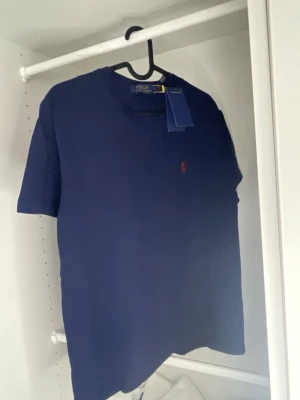 Zara t-shirt - Snygg mörkblå t-shirt från Zara med klassisk passform och korta ärmar. T-shirten har ett diskret rött broderat logomärke på bröstet och är tillverkad i mjuk bomull. Perfekt för dig som gillar stilrena basics. STÅR M MEN PASSAR S!!
