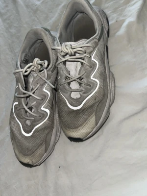 Beige sneakers med reflexdetaljer - Säljer ett par beige Adidas sneakers med coola reflexdetaljer och chunky sula. Skorna har meshmaterial på ovansidan och svarta detaljer på undersidan. Perfekt för dig som gillar streetstyle och vill sticka ut lite extra. Köpte nya för 1600