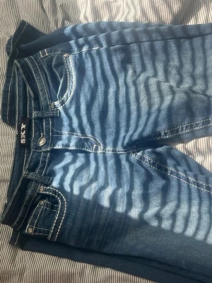 Blå jeans med broderade bakfickor - Snygga blå jeans från Sky med vit kontrastsöm och coola broderade detaljer på fickorna. Köpta i usa och bara använda ett fåtal gånger 