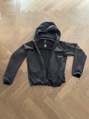 vindjacka Sail Racing - Tja säljer en snygg svart vindjacka från Sail Racing med luva och dragkedja. Den är i superfint skick och det märks knappast att den är använd. Ställ frågor om ni undrar något!