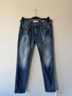 Replay Anbass - HELT OANVÄNDA! Jeans från Replay Anbass med slitningar och ljusa partier på låren. Jeansen har klassisk femficksdesign, Materialet är denim och passformen är slim fit. Perfekt för dig som gillar en avslappnad och trendig look.