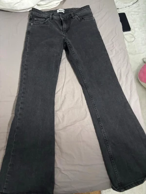 Svarta bootcut jeans från lager 157 - Säljer ett par svarta bootcut jeans från märket lager 157. Jeansen har klassisk femficksdesign, låg midja och utsvängda ben med lätt utsvängd form. Materialet är denim och färgen är mörkgrå/svart. Perfekt för dig som gillar en avslappnad och trendig look.