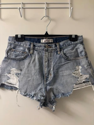 Hollister ljusblå denim shorts - Ljusblå denim shorts från Hollister med råa kanter och slitna detaljer. Perfekt för dig som gillar en avslappnad och trendig look.