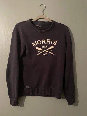 Morris mörkblå sweatshirt - Mörkblå sweatshirt från Morris med vit logotyp och text på bröstet. Tröjan har rund halsringning, ribbade muddar och är tillverkad i mjukt material. Perfekt för en avslappnad och stilren look.