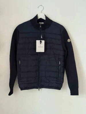 Monclear cardigan  - Riktigt fräsch cardigan från monclear. Den är hel svart, det ser ut som mörkblå men på sista bilden ser ni att den är hel svart. Rekommenderar folk som är mellan 180-190, eftersom den är mellan M/L