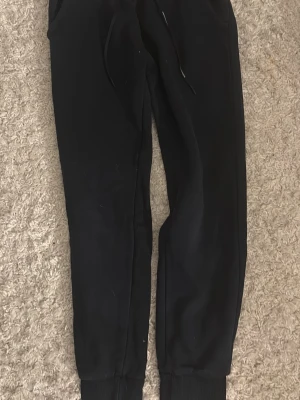 Svarta mjukisbyxor Peak Performance - Mysiga svarta mjukisbyxor från Peak Performance med ribbade muddar och dragsnöre i midjan. Byxorna har en skön fleeceinsida och klassisk passform 