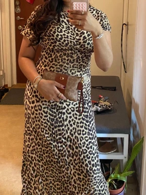 Leopardmönstrad klänning H&M - Snygg leopardmönstrad maxiklänning med korta ärmar och rund hals. Klänningen har en figurnära passform upptill och faller snyggt längs kroppen. Perfekt för dig som vill sticka ut med ett djurmönster. Materialet känns mjukt och följsamt.