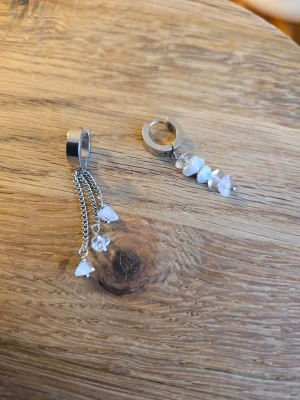Silvriga örhängen med naturliga stenar - Unika silvriga örhängen i två olika designer. Snyggt och trendigt accessoarval för dig som gillar detaljer. Materialet är rostfritt stål och stenchips, naturlig kvarts/bergkristall, 