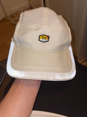 Nike Tn Air beige keps - Snygg beige keps från Nike med Tn Air-logga framtill. Kepsen har ventilerande meshpaneler upptill och böjd skärm. Perfekt för dig som vill ha en stilren och sportig look. Justerbar baktill för bästa passform. Är sparsamt använd och har tvättats ett flertal gånger. Kan gå ner i pris vid snabb affär