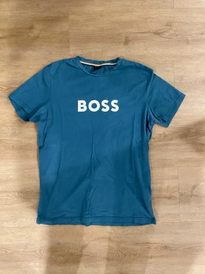 Hugo Boss T-Shirt - En Hugo Boss T-Shirt i mycket bra skick. Mycket bra kvalitet på tröjan och väldigt fin färg. Har ni frågor så är det bara att ställa de 😊