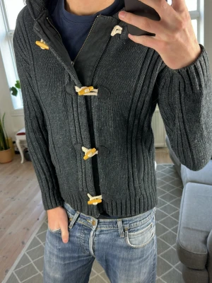 Stickad Cardigan med Luva  - Unik och väldigt snygg! Mått: A:44 B:43 C:43 D:60 (cm) Obs storleken är L men passar M. Färg:mörkgrå/svart. Skriv vid fundering! 😊✌️