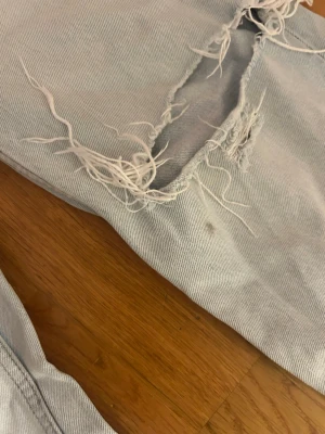 Ljusblå ripped jeans & other Stories - Säljer ett par ljusblå jeans från & other Stories med stora slitningar och hål på benen. Jeansen har klassisk femficksmodell, dragkedja och knapp i midjan. Använt några gånger , en liten fläck BREVID ena hålet men inget man lägger märke till. Passar xs