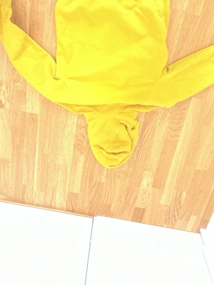 Gul hoodie från Peak Performance - Snygg gul hoodie från Peak Performance med klassisk huva och matchande snörning. Tillverkad i mjuk bomull, perfekt för dig som vill ha en färgklick i garderoben. Hoodien har en enkel och clean design som funkar till det mesta.