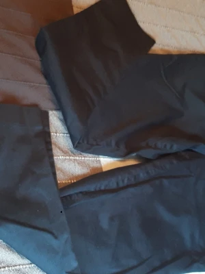 Navy blå kostymbyxor raka ben - Säljer ett par klassiska navy blå kostymbyxor med raka ben. Byxorna har en stilren look och är tillverkade i ett slätt tyg som ger en dressad känsla. Perfekta för dig som gillar enkel och tidlös stil. Storlek 44 EUR, 16 UK.