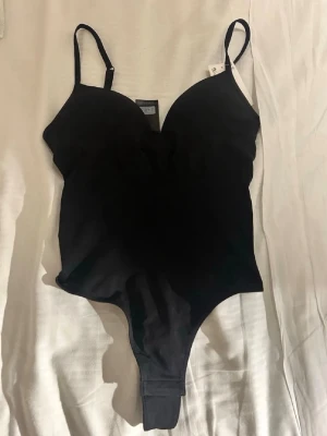 Svart body H&M - Populära bodyn från H&M med justerbara axelband och vadderade kupor. Tillverkad i ett stretchigt material som formar kroppen på ett smickrande sätt. 