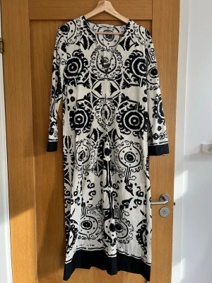Svartvit långklänning från Zara🤍🖤 - Unik långklänning, med tunika-känsla, från Zara i svartvitt med grafiskt mönster. Klänningen har lång ärm och rund halsringning. Tillverkad i ett mjukt material som känns skönt mot huden. Jättefint skick, i princip som ny! Perfekt för dig som vill sticka ut med en cool och konstnärlig look🤍🖤