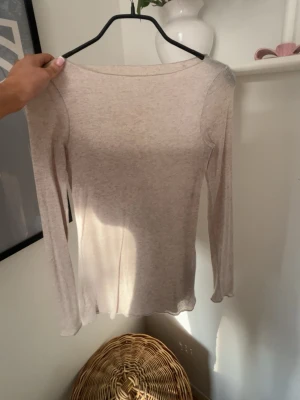 Beige långärmad topp i bomull - En enkel och stilren beige långärmad topp med rund halsringning. Tillverkad i mjukt bomullsmaterial som känns skönt mot huden. Perfekt att matcha med jeans eller kjol för en clean look.