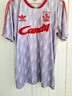 Glenn Hysén - Liverpool borta - 1989/1990 (L) - Säljer en klassisk fotbollströja, Glenn Hyséns  gråa Liverpool-matchtröja (borta) från 1989. Tröjan är en remake i nyskick.    Storlek: Large  Hör av er vid intresse. Har även hemmatröjan. 