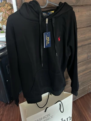Svart hoodie  Polo Ralph Lauren - Snygg svart hoodie från Polo Ralph Lauren med rött märke. endast testad inne en gång så skicket är helt nytt, storlek M men passar S bättre då dom är små i storlekarna skriv vid minsta fundering eller om man vill ha fler bilder 🤩