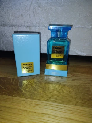 Tom Ford Mandarino di Amalfi EdP 100ml - Tom Ford Mandarino di Amalfi Eau de Parfum i en lyxig blå glasflaska med guldiga detaljer. Flaskan rymmer 100 ml och kommer med en matchande blå kartong. En exklusiv parfym med fräsch citrusdoft och elegant design.