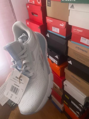 Ljusblå Reebok sneakers - Snygga ljusblå sneakers från Reebok med ventilerande meshmaterial och klassisk logga på sidan. Skorna har en låg silhuett, vita snören och en bekväm, dämpad sula som passar perfekt till en sportig och avslappnad stil.