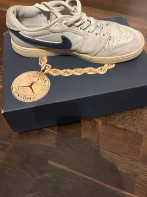 Jordan 1 low ajko union la 43 sail - En collab mellan Union Los Angeles och Jordan. Skorna är använda men fortfarande användbara. En del slitage på sulan och lite slitage bak på skorna som knappt syns vid användning. Skon är gjord i högkvalitativt läder (jämfört med andra jordans) och mocka. Skorna kommer med utbytbara Nike swoosh i blå och grön. Storlek 43. Kommer i original låda. Passar dig som vill ha på dig något som känns premium och som vill kunna matcha ett par skor med många outfits. Nypris resell: cirka 1700 kr