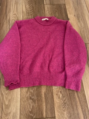 Mörkrosa stickad tröja Pull&Bear - Säljer en mörkrosa stickad tröja från Pull&Bear. Tröjan har en rak passform, ribbstickade muddar vid ärmslut, nederkant och halsringning. Perfekt för att hålla sig varm under kyliga dagar.