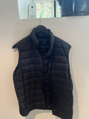 Svart dunväst från Uniqlo - Säljer en svart väst från Uniqlo i storlek M. Lätt och smidig modell som är perfekt att ha över en hoodie, tröja eller skjorta. Väldigt praktisk för höst, vår eller kyliga sommarkvällar. Enkel och stilren design som passar till det mesta. Använd men fortfarande i bra skick. DRAGKEDJAN ÄR TRASIG Storlek: M Märke: Uniqlo Färg: Svart Skriv gärna om du har frågor!