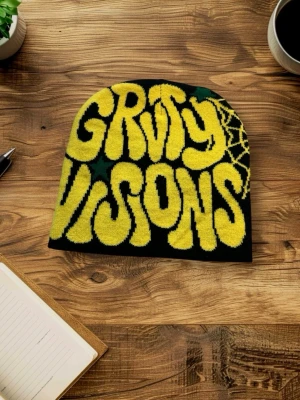 Svart mössa med gul text och spindelnät - Cool svart mössa med stor gul text 'GRVY VISIONS' och stjärnor på framsidan. Baksidan har ett gult spindelnätsmönster. Materialet är stickad bomull eller akryl, perfekt för att ge din stil en unik touch.