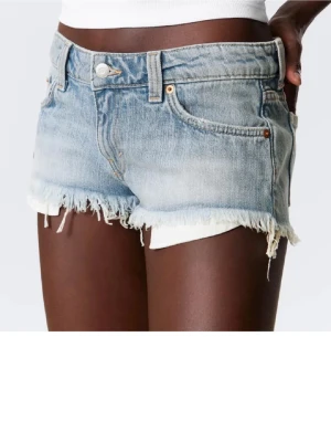 Weekday Ljusblå denimshorts med fransig kant w 26 - Weekday ljusblå denimshorts med fransig rå kant och klassisk femficksdesign. Shortsen har låg midja och är tillverkade i bomull. Perfekta för varma dagar och en avslappnad stil . W 26. Slutsålda 